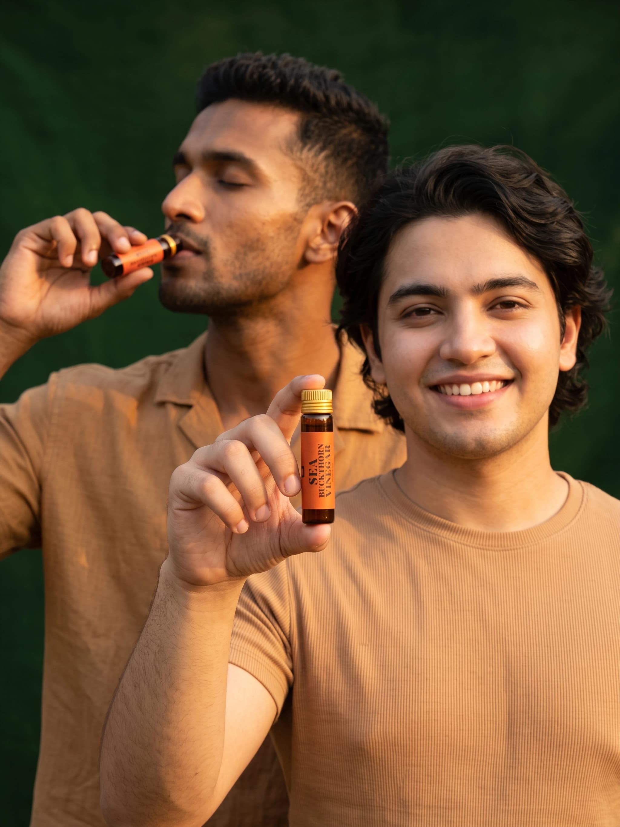 A man drinking Sea Buckthorn Vinegar beside a smiling man holding a bottle